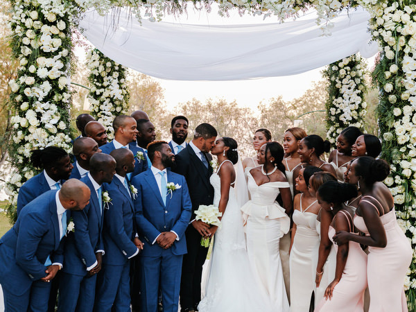 Bridal party laughing together under white flower canopy at Ble Azure luxury Nigerian destination wedding.