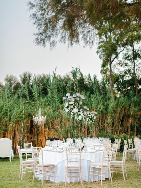 Round reception tables with white linens and floral centerpieces at Island Resort The Residence Nigerian wedding in Athens.
