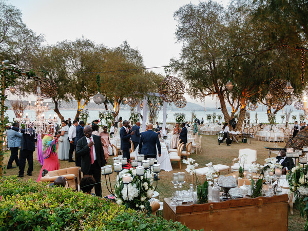 Guests mingling during outdoor reception at Island Resort The Residence luxury Nigerian wedding in Athens Riviera.