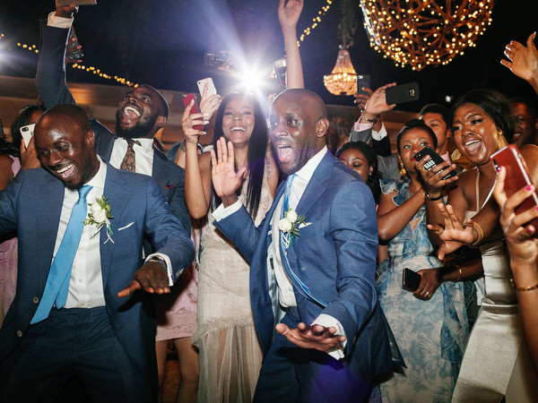 Groomsmen dancing at Island Resort The Residence during glamorous Nigerian destination wedding in Greece.