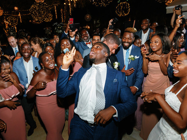 Groomsmen dancing surrounded by cheering guests at Island Resort The Residence luxury Nigerian wedding reception.