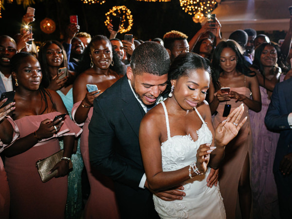 Bride and groom dancing together under chandeliers at Island Resort The Residence Athens wedding reception.