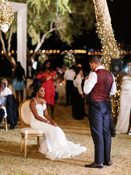 Bride seated during reception while groom speaks at Island Resort The Residence luxury Nigerian wedding in Athens Riviera.