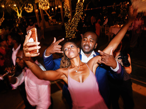 Wedding guests taking selfies while dancing at Island Resort The Residence Nigerian wedding in Greece.
