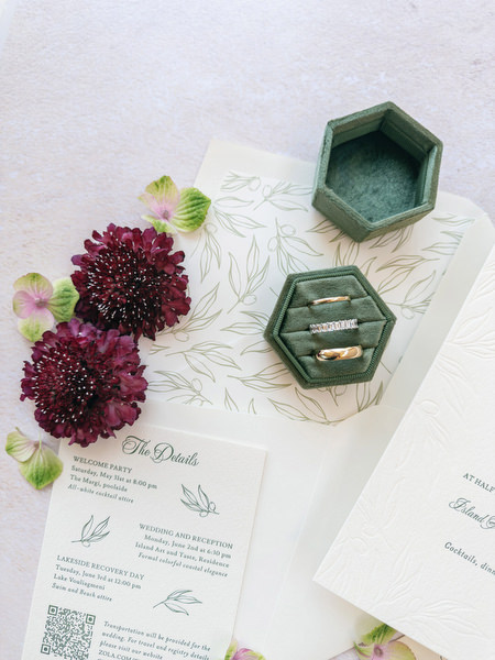 Gold wedding bands displayed beside Jewish wedding program and floral accents