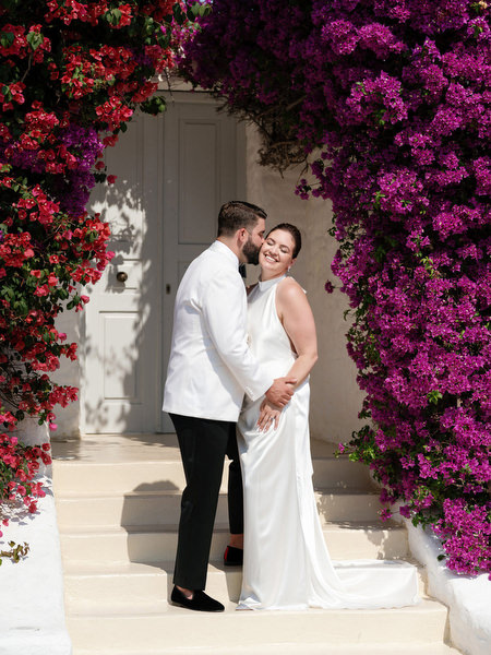 Bride and groom sharing intimate kiss framed by pink bougainvillea