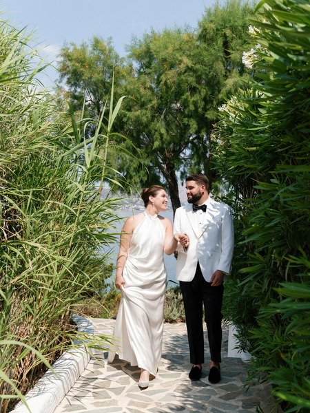 Bride and groom walking together along greenery-lined path at Island Resort