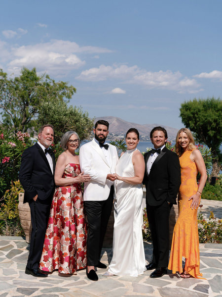 Bride and groom standing with close family members overlooking the Athenian Riviera