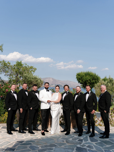 Groom surrounded by groomsmen in black tuxedos at Island Resort Athens
