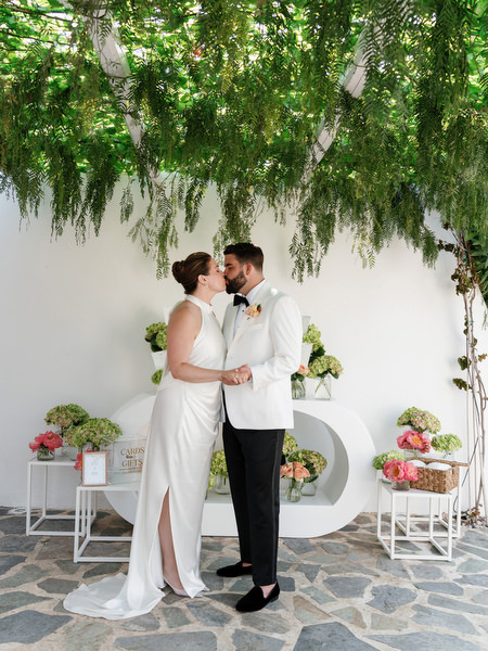 Bride and groom standing together under lush hanging foliage before ceremony