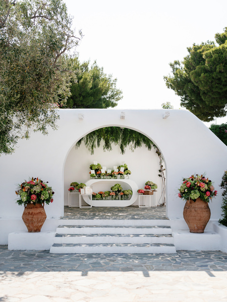 White arched entrance space decorated with coral and blush flowers on the Athenian Riviera