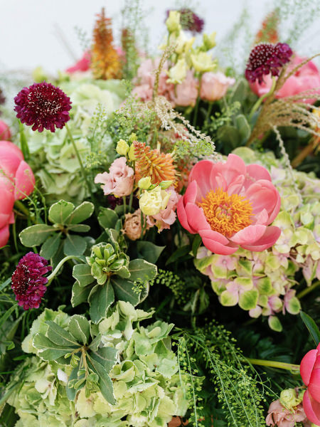 Detailed arrangement of coral peonies and textured greenery for Jewish wedding ceremony