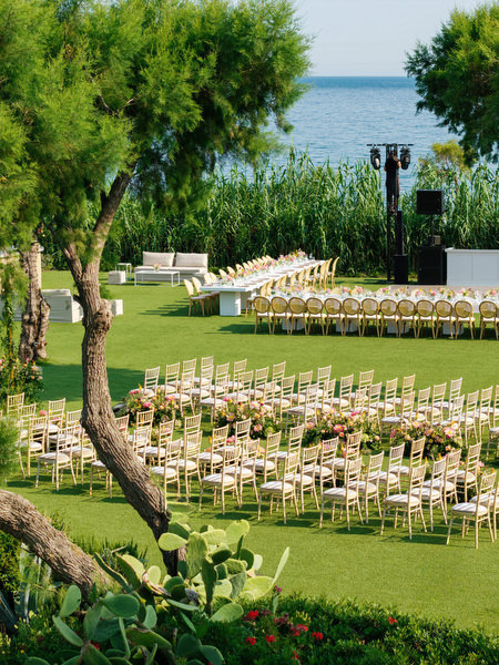 Gold ceremony chairs arranged on manicured lawn facing the Athenian Riviera at Residence venue