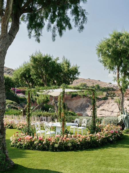 Round chuppah structure surrounded by blush and coral flowers against coastal backdrop at Residence venue