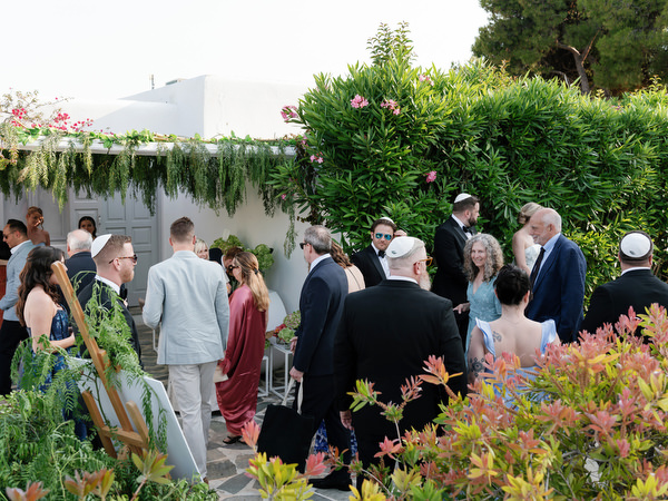 Family and friends mingling in garden courtyard before Jewish ceremony