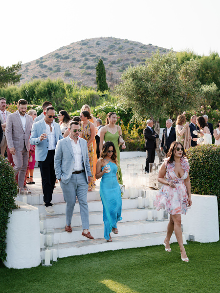 Wedding guests arriving down white stone steps toward Island Residence seaside ceremony lawn