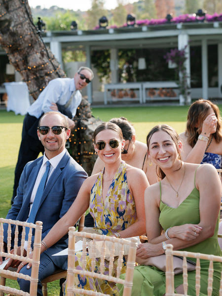 Friends seated in gold chairs, smiling in anticipation before chuppah ceremony at Island Residence