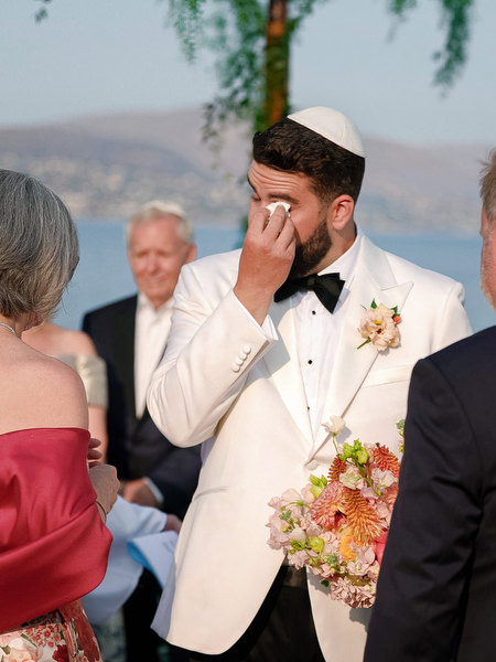Groom wiping away tears during bride’s entrance at Jewish ceremony