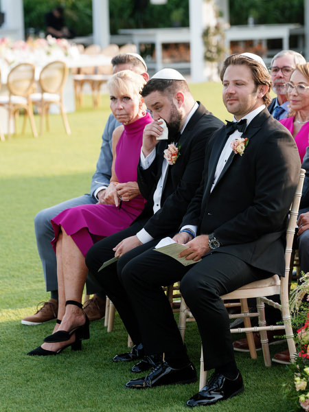 Groomsman emotional during vows as guests watch closely