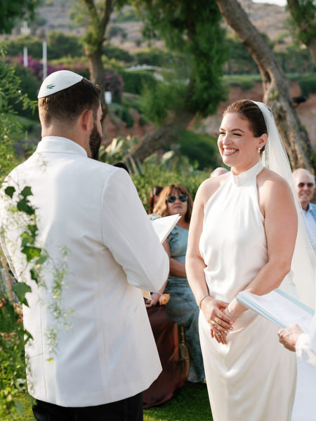 Bride laughing softly as vows are exchanged beneath the chuppah