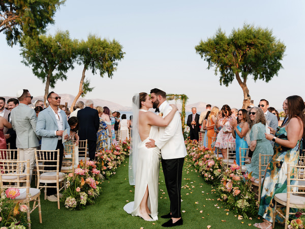 Couple kissing down the aisle as guests applaud and celebrate at Island Residence