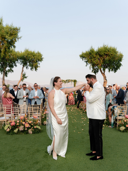 Bride twirling groom playfully on the lawn surrounded by cheering guests