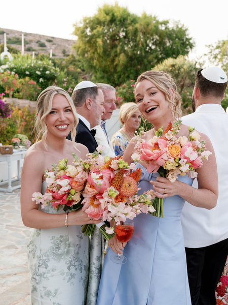 Bridesmaids smiling with vibrant coral and blush arrangements