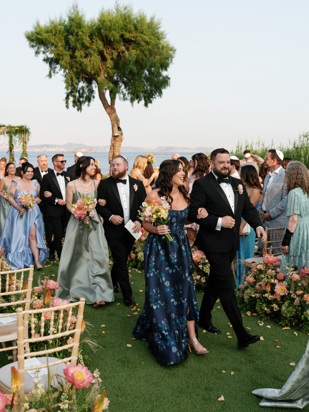 Bridal party and guests walking joyfully down the floral-lined aisle post-ceremony