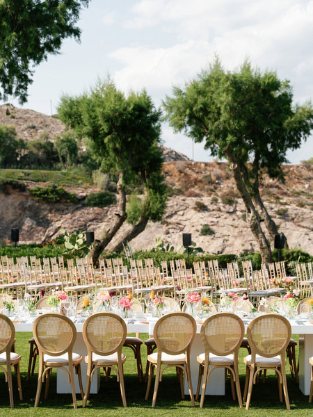 Elegant rattan chairs and long banquet tables set against Mediterranean hills at Island Residence