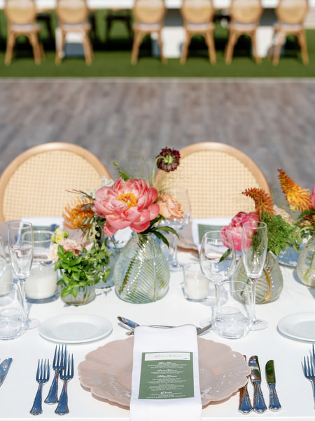 Reception table styled with coral peonies, hydrangeas, and soft glassware at Island Residence