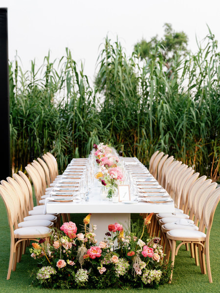 Elegant rattan chairs and long banquet tables set against Mediterranean hills at Island Residence