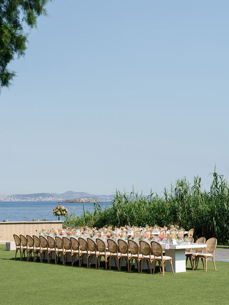 Long banquet tables arranged on manicured lawn overlooking the sea at Island Residence