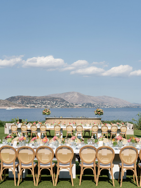 Rattan chairs and floral-lined tables set against the Athenian Riviera horizon at Island Residence