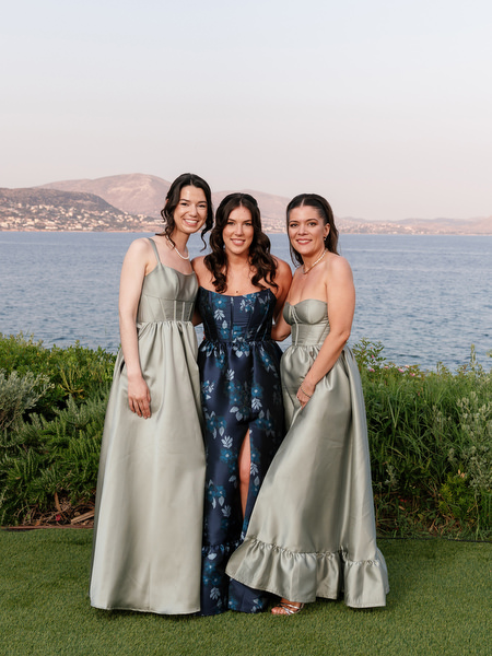 Bridesmaids in sage and navy gowns posing with the coastline backdrop