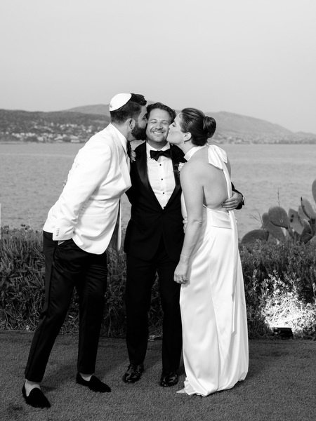 Bride and groom sharing a playful kiss surrounded by friends