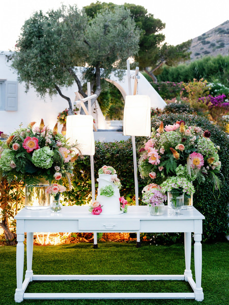 Lush greenery and coral blooms framing a styled reception display table at Island Residence