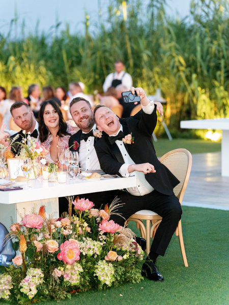 Guests leaning in for a joyful selfie during dinner
