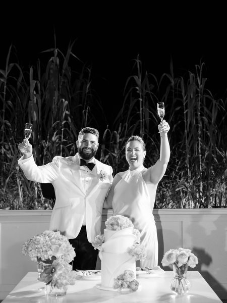 Bride and groom raising glasses before cutting the cake at Island Residence