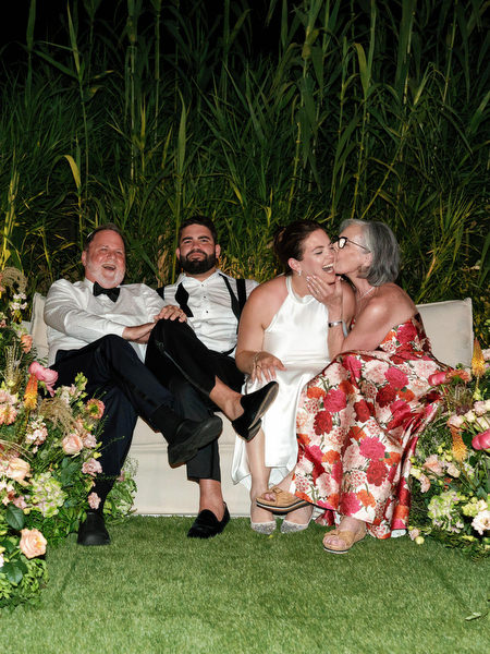 Bride laughing with family members surrounded by coral and blush florals at Island Residence