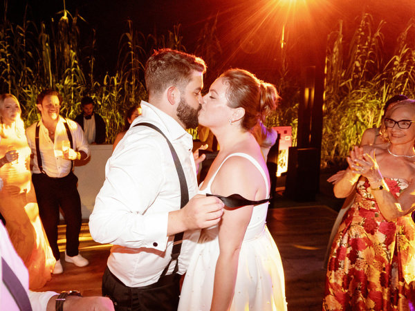 Bride and groom sharing a kiss under colorful party lighting at Island Residence