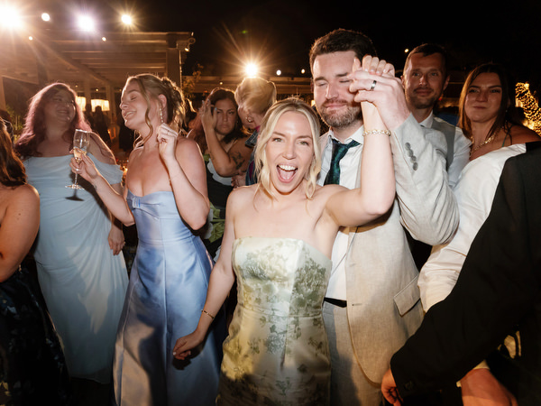 Friends cheering and dancing beneath warm reception lights at Island Residence