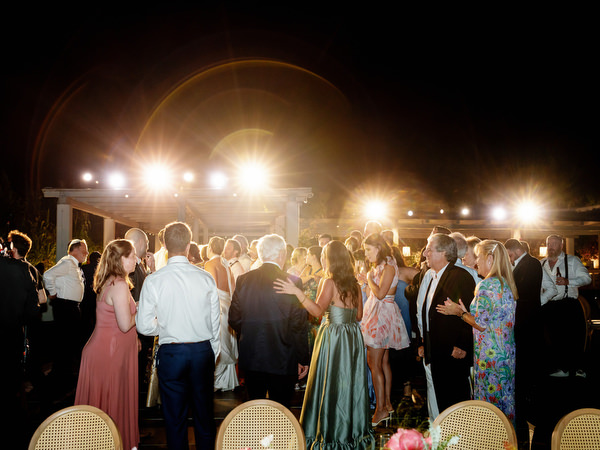 Full dance floor glowing under string lights on the Athenian Riviera