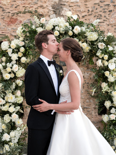 Bride and groom portrait under floral arch at Kinsterna Hotel Monemvasia.