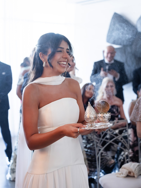 Bride's sister holding Greek Orthodox wedding crowns during pre-ceremony traditions in Athens