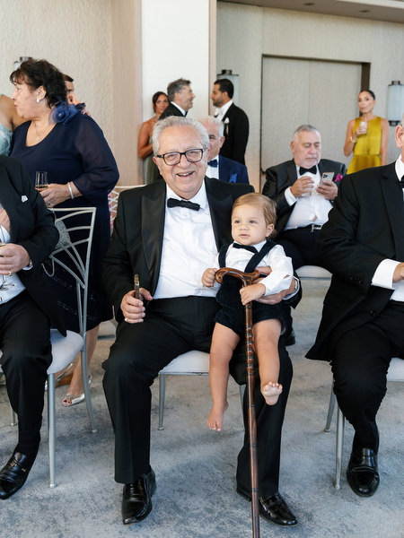 Grandfather holding a child during family wedding celebrations in Athens