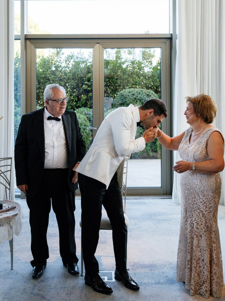 Groom kissing his mother’s hand during traditional Cypriot wedding customs in Athens