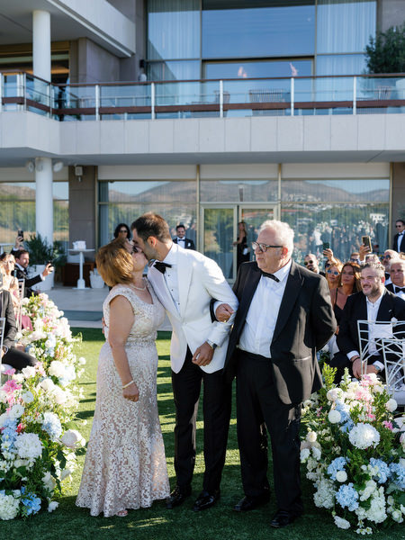 Groom greeting family members before the outdoor wedding ceremony in Athens