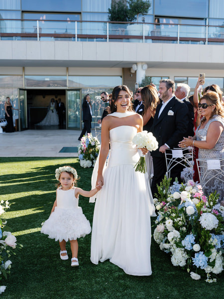 Bridesmaid walking down the aisle with flower girl during a Four Seasons Athens wedding ceremony
