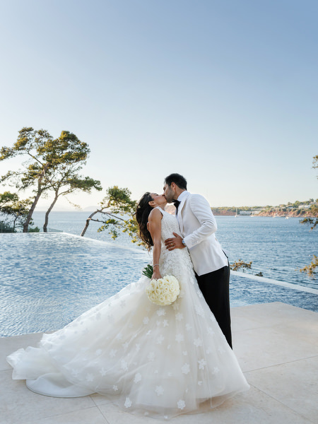 Bride and groom kissing with Aegean Sea backdrop at Four Seasons Astir Palace