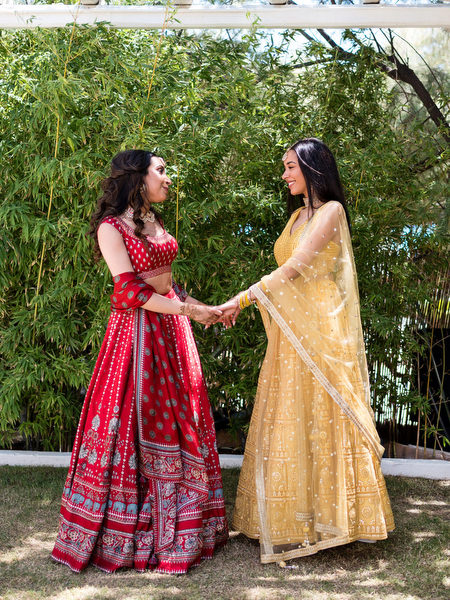 Bride and brides sister laughing during colorful Mehndi event